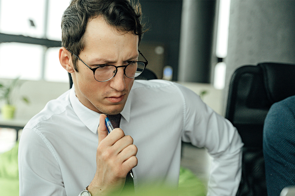 Man thinking with pen in hand