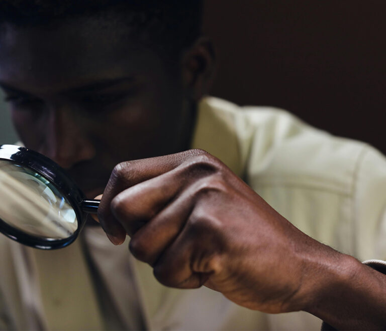 Man holding magnifying glass to his eye